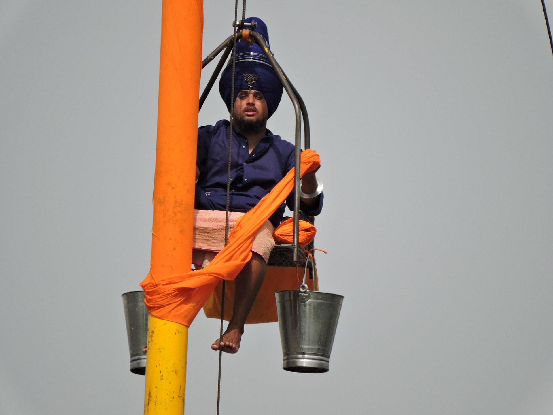 A Nihang Singh renewing the chola of a Nishan Sahib